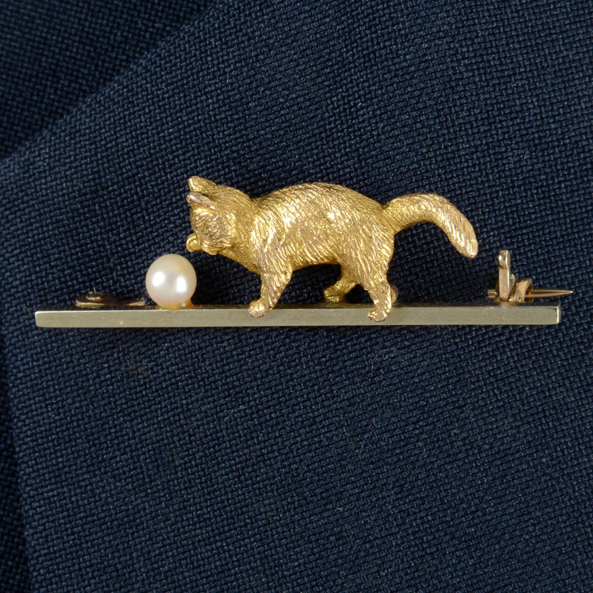 An Edwardian 9ct gold seed pearl bar brooch, designed as a kitten playing with a ball.