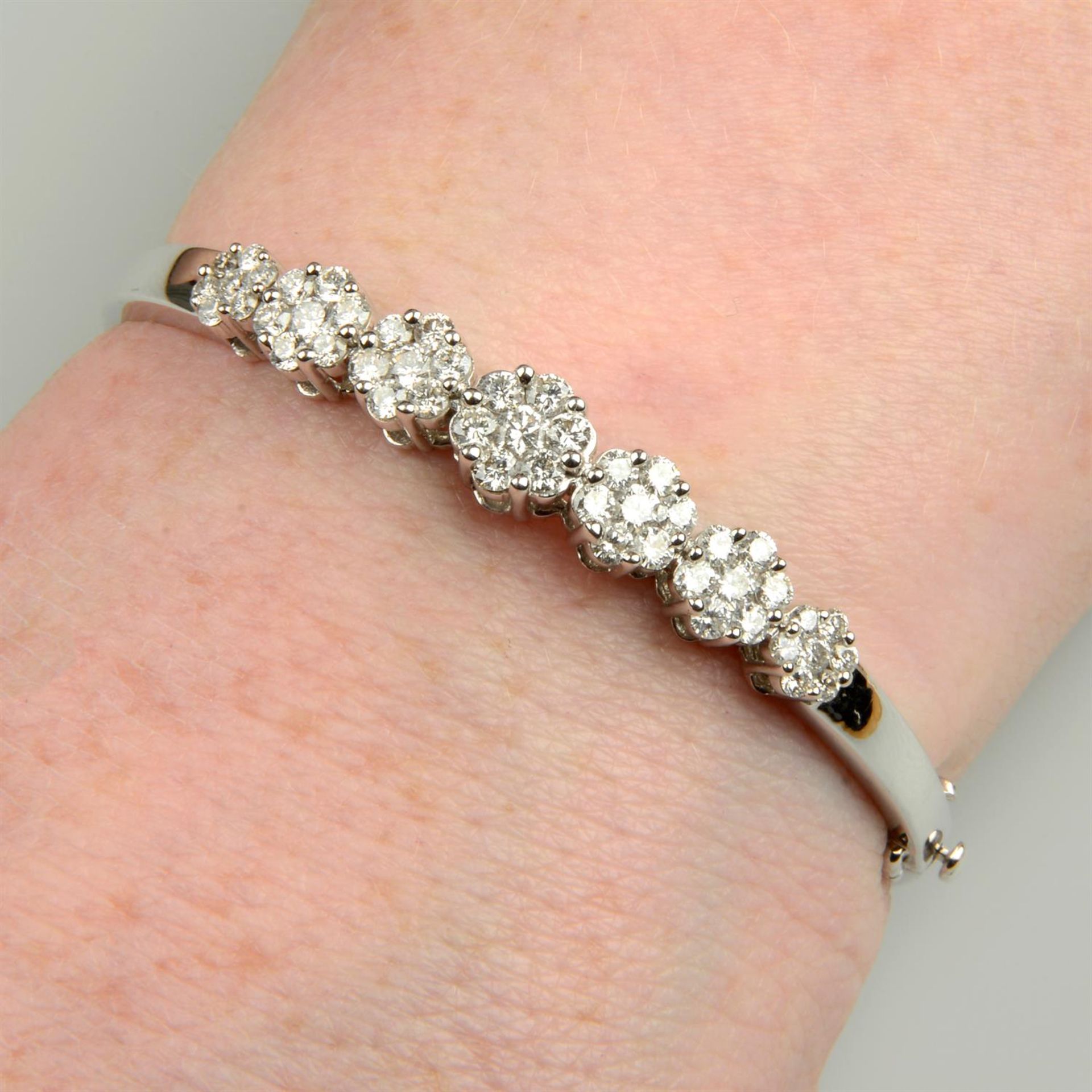 An 18ct gold brilliant-cut diamond cluster hinged bangle.