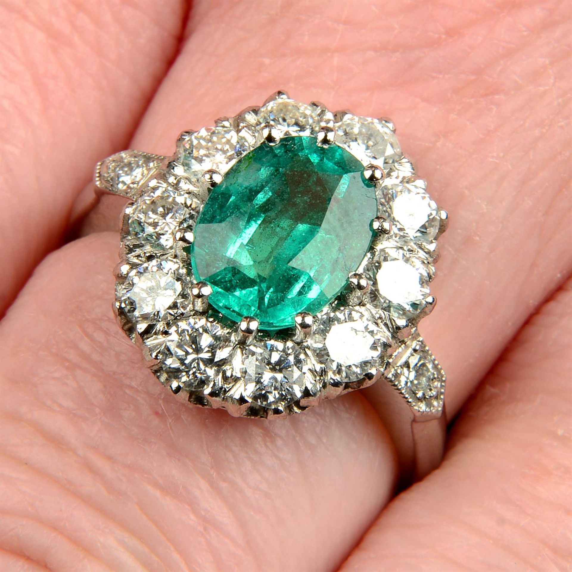 An emerald and brilliant-cut diamond cluster ring.