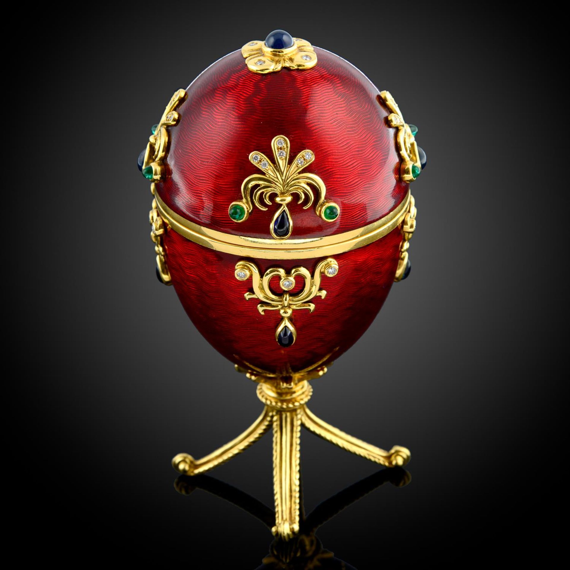 A limited edition red enamel and multi-gem egg sculpture, with hinged portrait interior,