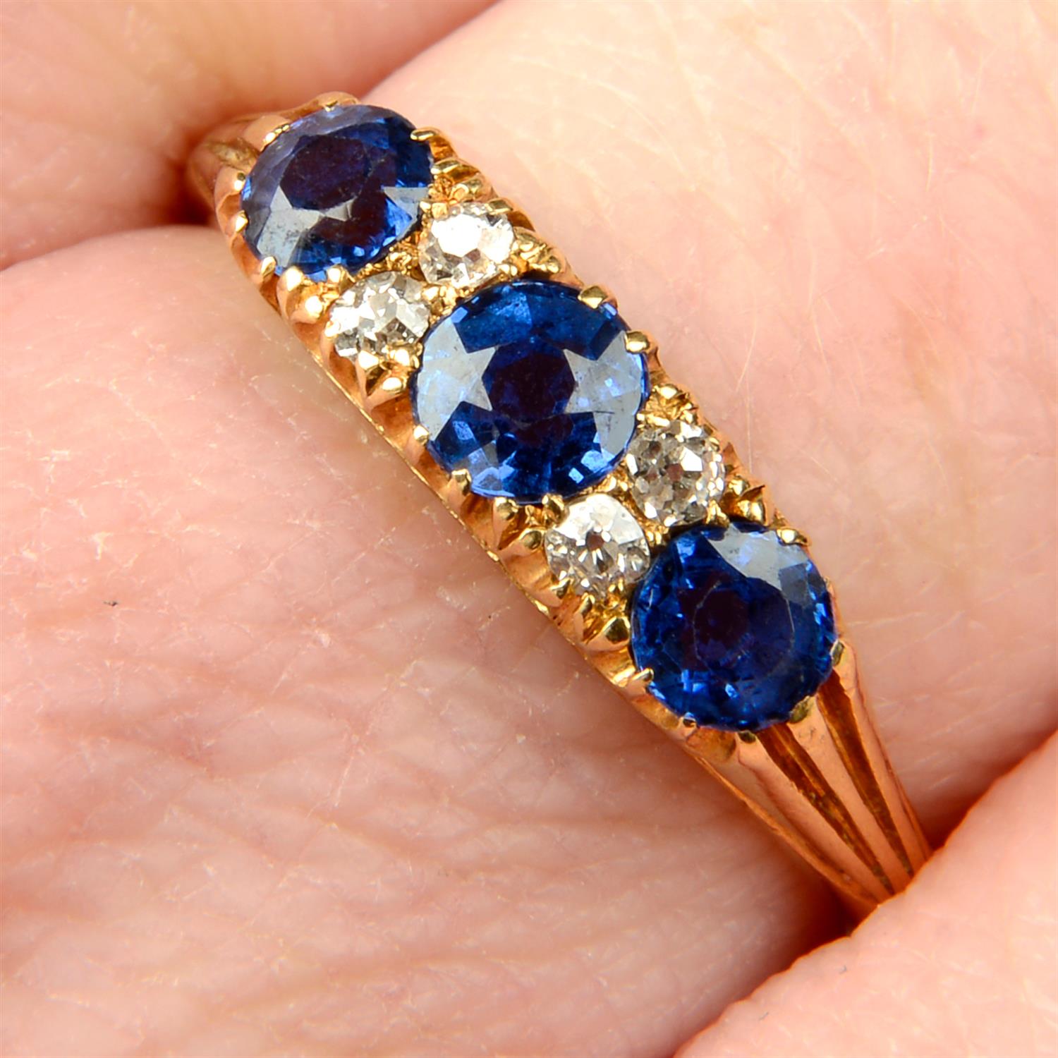 An early 20th century 18ct gold sapphire three-stone ring, with old-cut diamond double spacers.