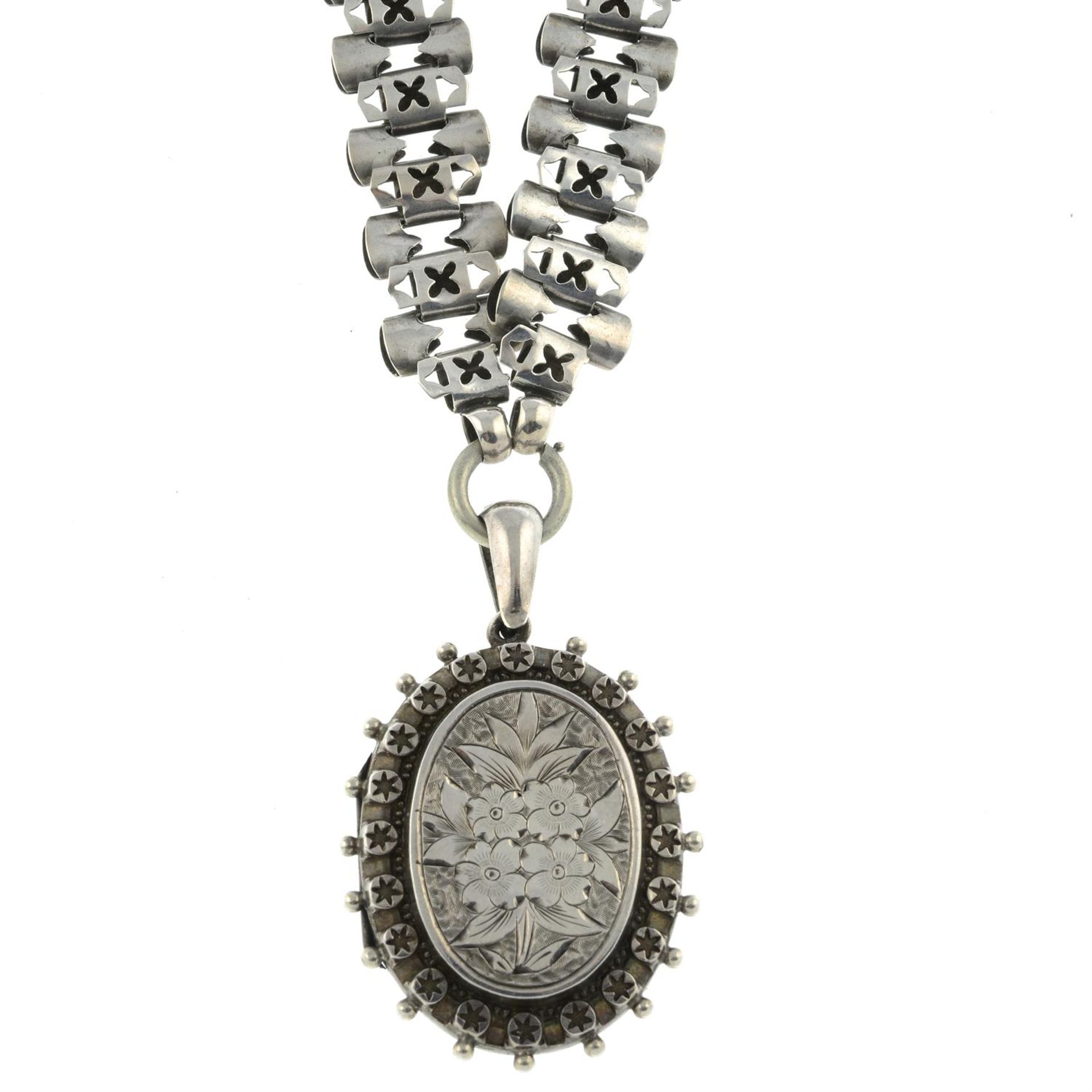 A late Victorian silver floral engraved locket, with chain.