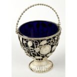 A white metal openwork sugar basket with swing handle & blue glass liner.