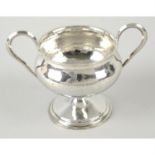 An Arts & Crafts style hammered silver twin-handled cup by Omar Ramsden.