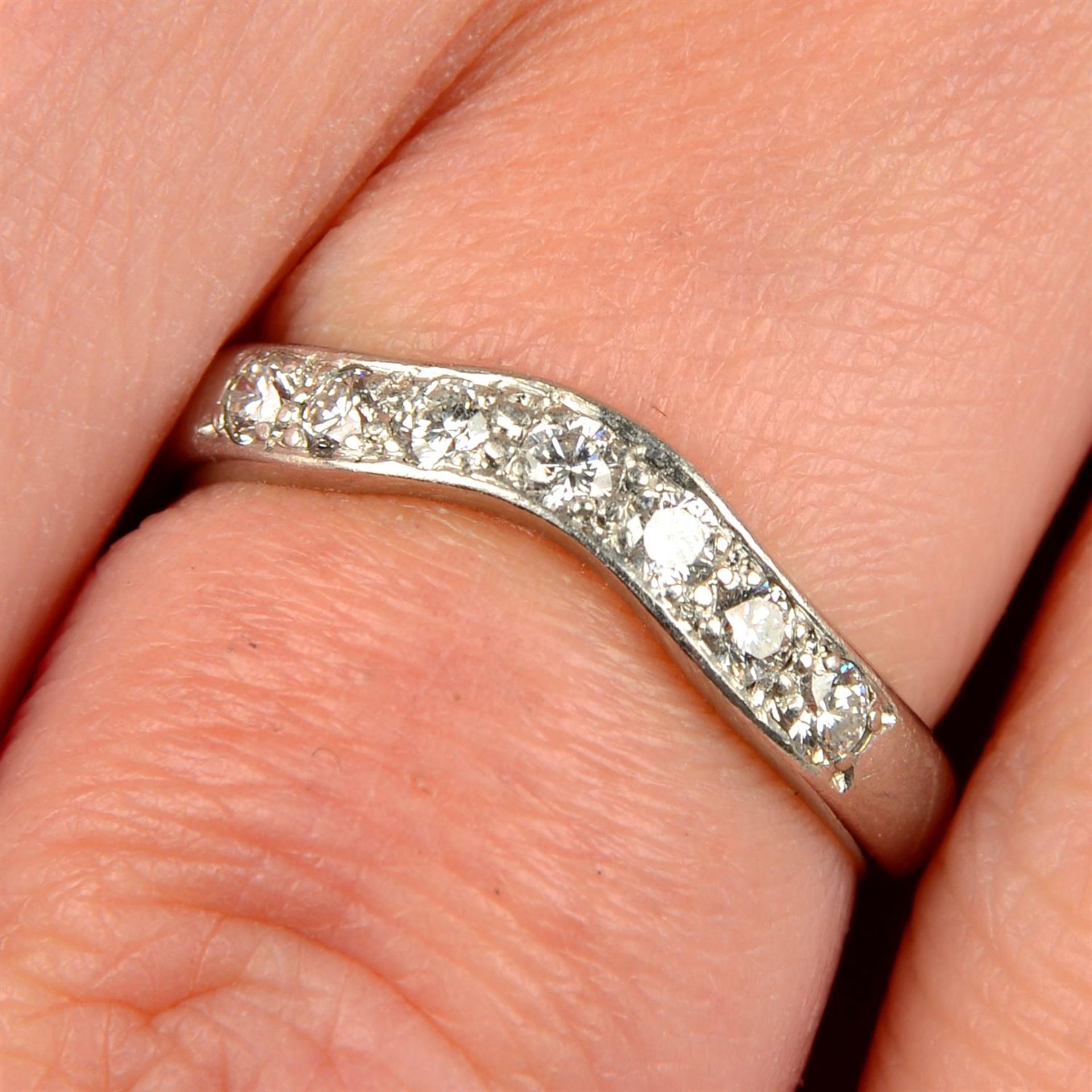 A platinum brilliant-cut diamond seven-stone shaped band ring.