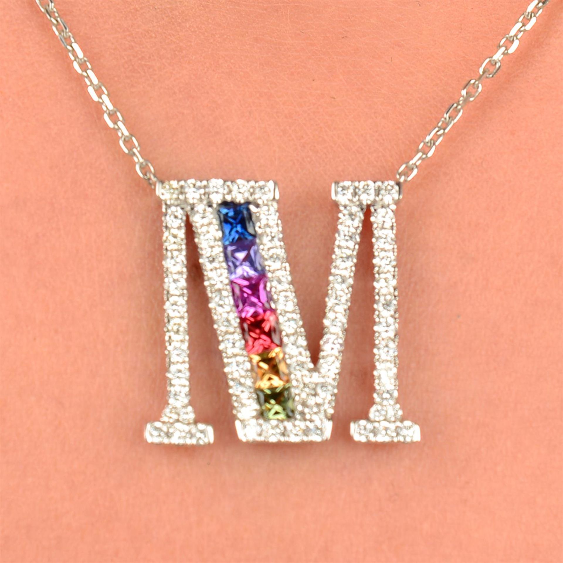 A vari-hue sapphire and brilliant-cut diamond initial 'M' pendant, on chain.