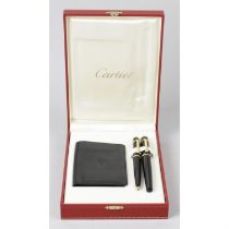 A Cartier 'Diabolo' ball point pen, a similar example, and a Cartier credit card case. (3)