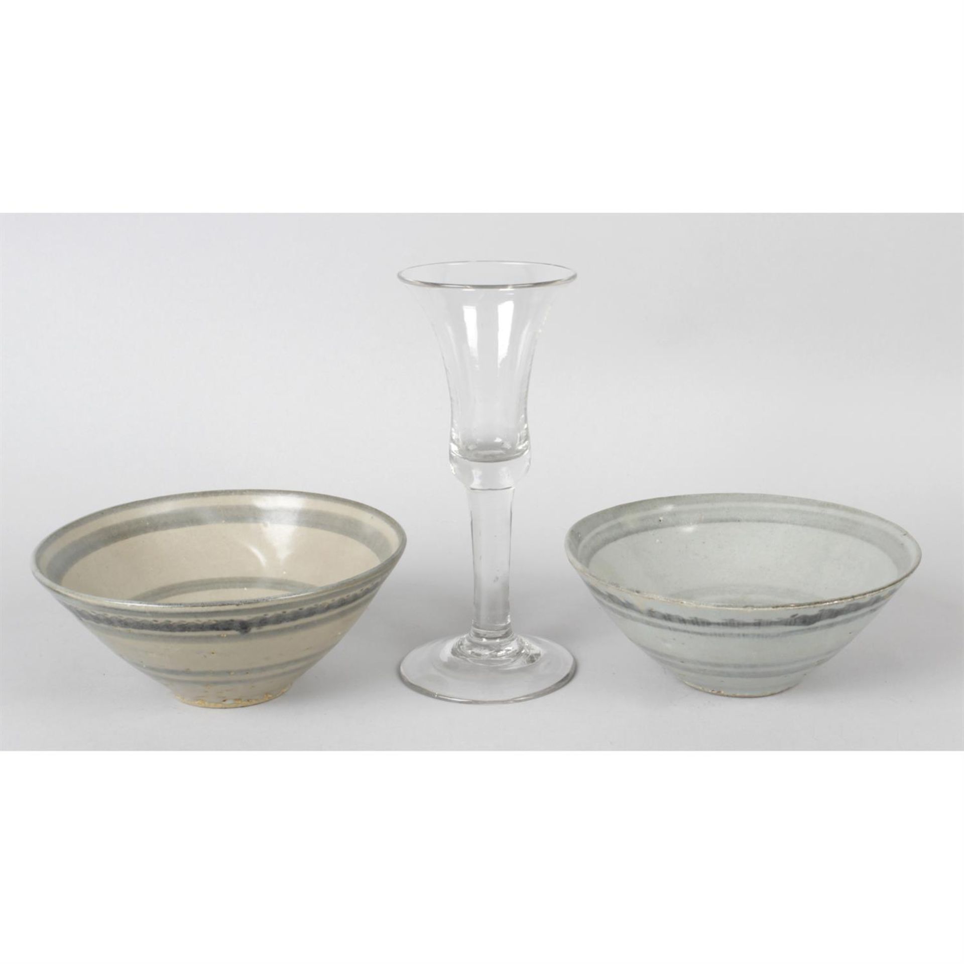 An antique wine glass, together with two Chinese pottery bowls.
