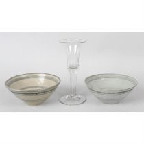 A wine glass and two Chinese pottery bowls.