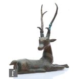 A Tibetan/Himalayan cast metal figure of a recumbent stag, head alert and turned with a foreleg