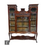 An Edwardian triple door mahogany display cabinet enclosed by glazed doors with carved panelled