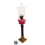 An Edwardian brass oil lamp, ruby shade on stepped lion mask base, height 72cm.