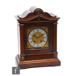 An early 20th Century walnut cased mantle clock with eight day movement striking on a gong, on