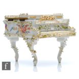 An early 20th Century Dresden type table top box and cover formed as a grand piano with floral
