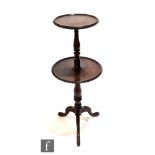 An early 20th Century mahogany two tier dumb waiter, turned baluster pedestal on splayed tripod