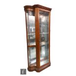 A late 20th Century walnut finish floorstanding serpentine glazed display cabinet enclosed by a