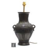 A Chinese cast metal archaic vase, Hu, rising from a high footring and applied with two loop and