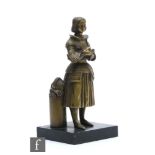 A 19th Century gilt metal figure of Joan of Arc standing with folded hands near her helmet and a