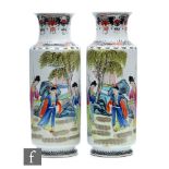 A pair of Chinese 20th Century rouleau vases, each of the white glazed bodies decorated with figures