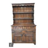 A small 17th Century style oak dresser and rack, fitted two short drawers over a cupboard base,