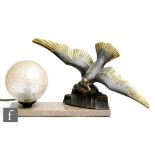 An Art Deco table lamp modelled as a bronzed spelter seagull in flight above a crashing wave with