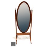 An Edwardian inlaid mahogany oval cheval mirror supported by two brass final uprights, on splayed