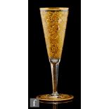 A late 19th Century continental champagne glass with funnel bowl with heavily gilded foliate