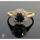 An 18ct hallmarked sapphire and diamond cluster ring, central circular sapphire within a diamond set