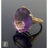 An 18ct single stone amethyst ring, oval claw set stone, length 8mm, weight 6.4g, to plain