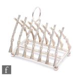 A 20th Century plated six divisioned toast rack in the form of flintlock rifles, width 11cm.