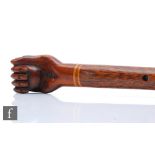 A 20th Century Polynesian hardwood walking stick, the end carved as a hand clasping a ball,