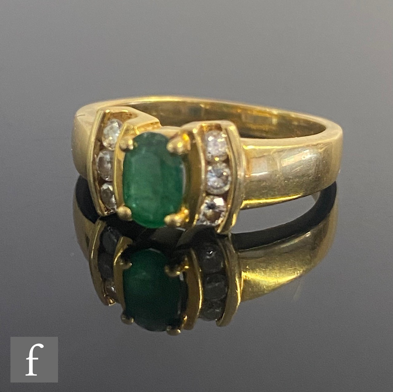 A modern 18ct hallmarked emerald and diamond ring, central oval emerald flanked by three diamonds to