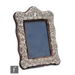 A hallmarked silver rectangular easel photograph frame with embossed foliate decoration to whole,