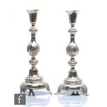 A pair of early 20th Century Russian silver candlesticks each with a circular dome base and part