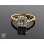 An early 20th Century 18ct emerald and diamond cluster ring, central emerald cut emerald within a