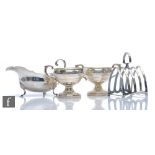Four items of hallmarked silver to include a toast rack, a pedestal sugar and cream,