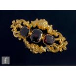 A 19th Century 9ct three stone garnet set brooch with part engraved scroll decoration, weight 10g,