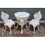 A heavy white painted circular cast iron garden table and a pair of matching chairs on scroll