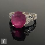 An 18ct hallmarked white gold ruby and diamond ring, central oval claw set ruby, length 11.5mm,