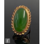 A 9ct single stone ring, central oval collar set nephrite to a pierced crimped border, weight 8.