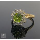 An 18ct hallmarked peridot and diamond cluster ring, central peridot within a border of twelve
