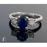An 9ct white gold sapphire and diamond three stone ring, central oval sapphire flanked by illusion