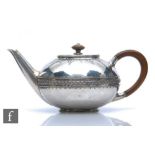 A hallmarked silver circular tea pot with a central woven effect frieze below fruiting vine details,