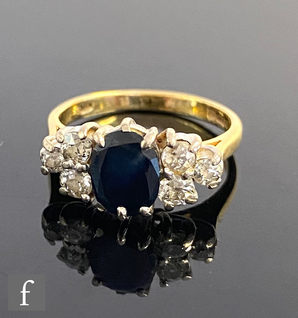 An 18ct hallmarked sapphire and diamond ring, oval central sapphire flanked by three brilliant cut