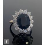 A 9ct sapphire and cubic zirconia cluster ring, central sapphire within a border of fourteen cubic