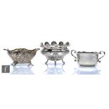 A hallmarked silver twin handled bowl raised on four scroll feet, with a similar sugar basin,