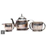 An Edwardian silver three-piece solitaire tea service, comprising a teapot, a twin handled sugar