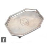 A George III octagonal teapot stand, engraved with a crest and monogrammed, raised border, on