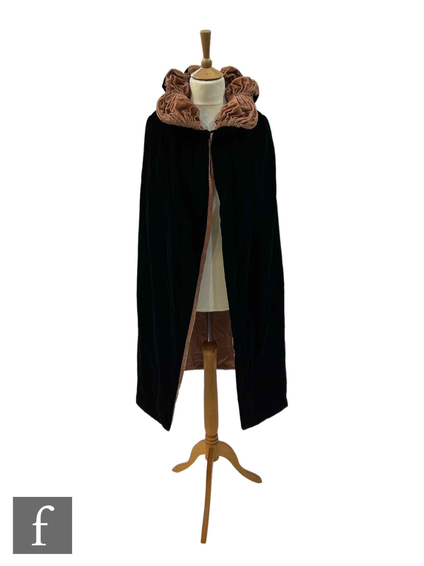 A 1920s reversible opera cape in black velvet with salmon pink lining and ruched padded collar.