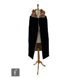 A 1920s reversible opera cape in black velvet with salmon pink lining and ruched padded collar.